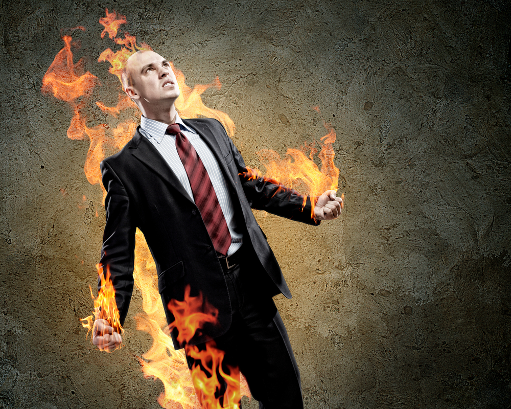 Image of young businessman in anger burning fire
